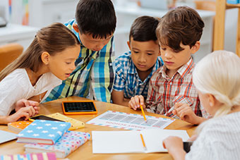 Children of different nationalities around a classroom desk