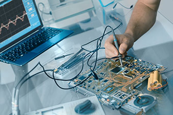A person using a probe to test a PCB on his laptop