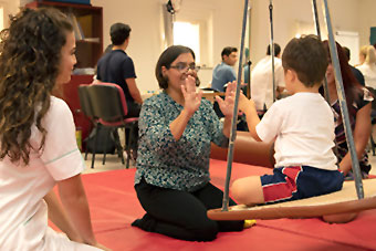 A professional during an occupational therapy session with a child, other people in the background
