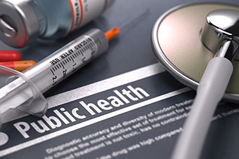 A syringe, a stethoscope, a small bottle and a sheet of information with the word public health on it
