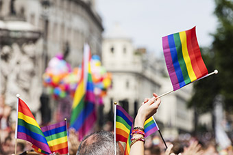 A number of people waving the rainbow flag