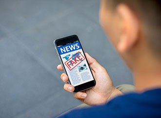 Fake news, hoax concept; close-up of man hands holding mobile phone