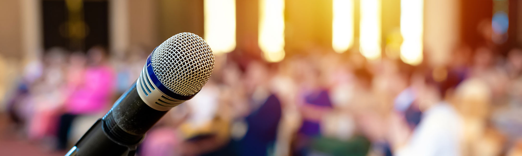 Microphone with a blurred conference setting in the background.