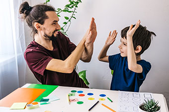 Happy autism boy during therapy with school tutor, learning and having fun together