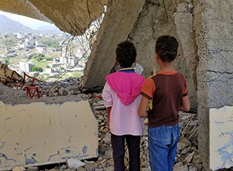 Children looking at city in ruins as a result of war