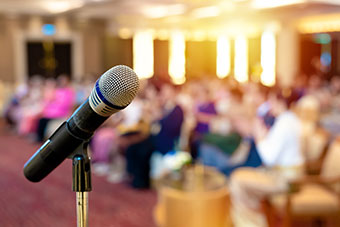 Microphone with a blurred conference setting in the background.