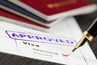 Visa form close up, fountain pen and approved stamped on a document.