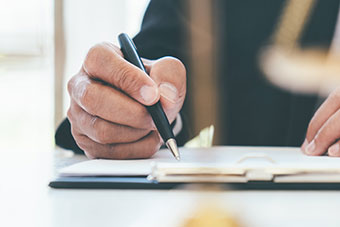 Hand with pen writing a document