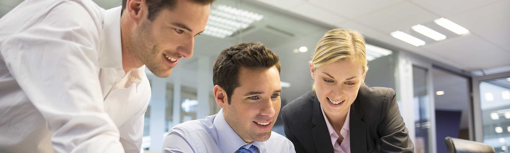 Three people in an office looking at a computer screen