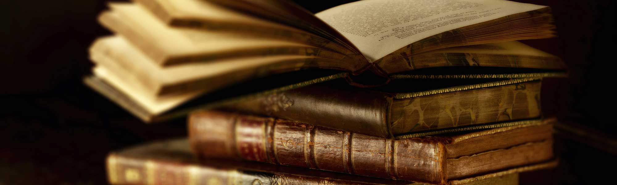 A pile of old books having the top one open