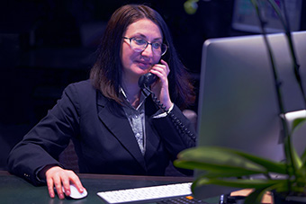A female talking on the phone and looking at a computer monitor