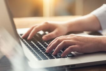 A detail of a person typing on a laptop