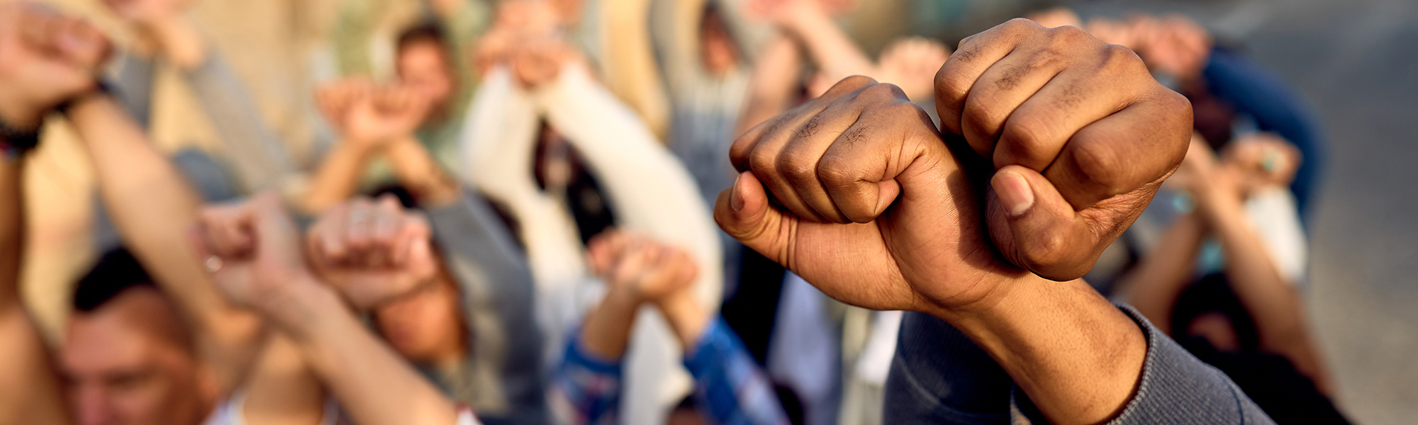 Close-up of large group of protesters with clenched fists above their heads on public demonstrations.