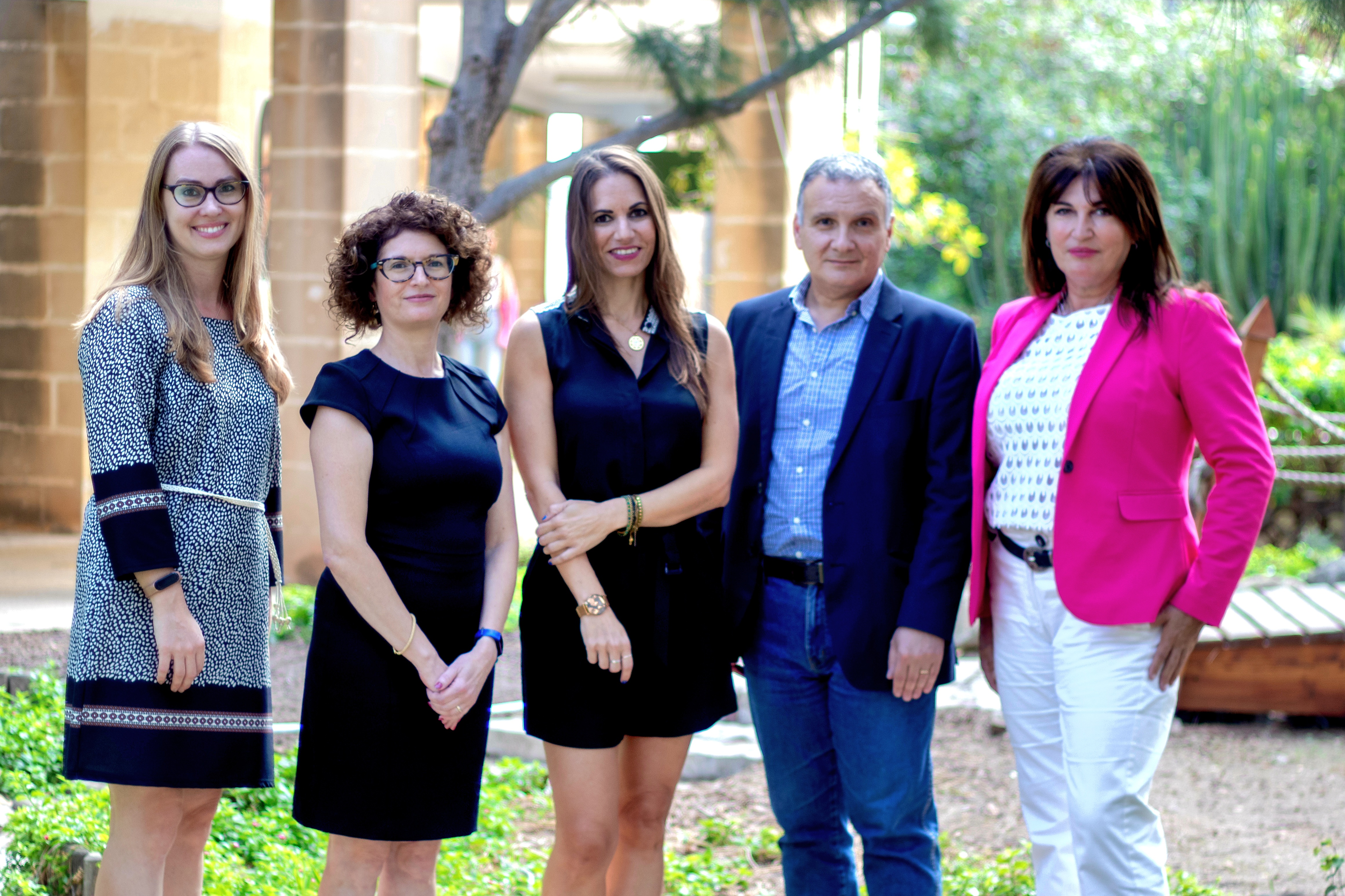 5 ACADEMIC STAFF MEMBERS STANDING NEXT TO EACH OTHER OUTDOORS IN THE JAPANESE GARDEN ON CAMPUS