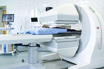 Gamma camera in the parlour of the clinic of nuclear medicine and patient undergoing a medical examination.