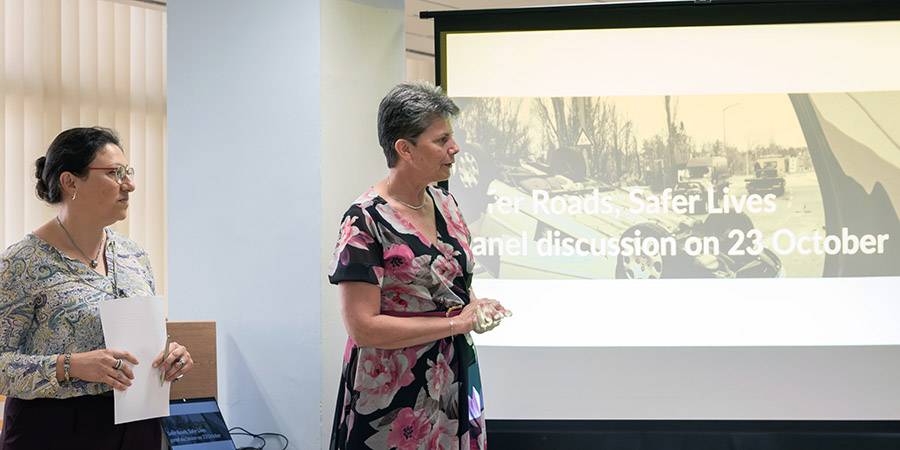 Two speakers during a discussion, next to a large screen