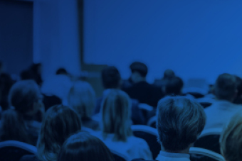 Audience seated and facing a presentation screen