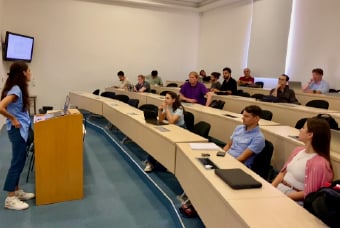 Person giving a presentation to a small audience in a lecture room.