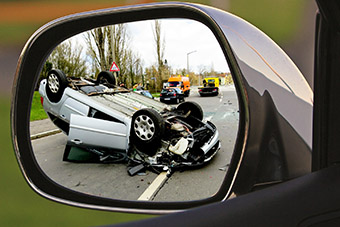 A crashed car seen through a car's side mirror
