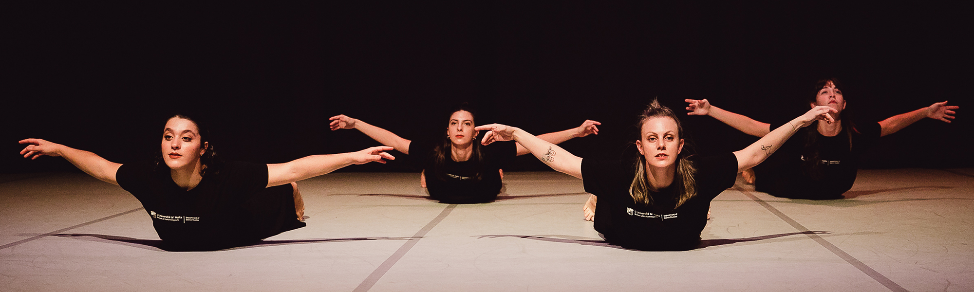 four dancers on floor stretching up