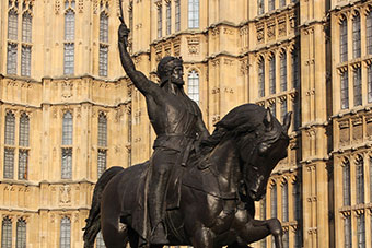 A bronze statue with a knight on horseback and a building in the background