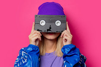 A person holding a cassette tape in front on the face