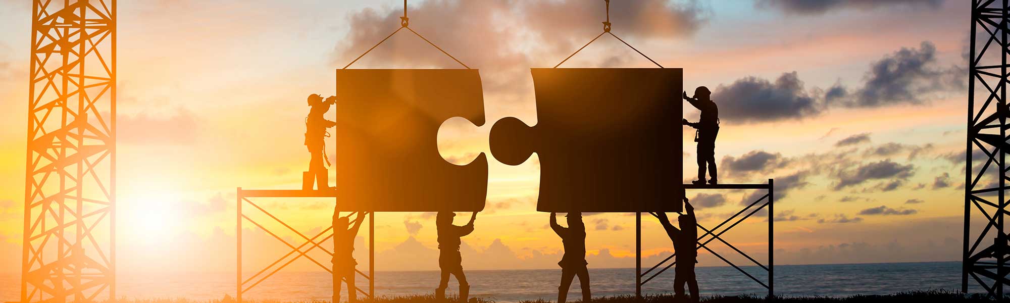 Workers holding two puzzle pieces connecting them together